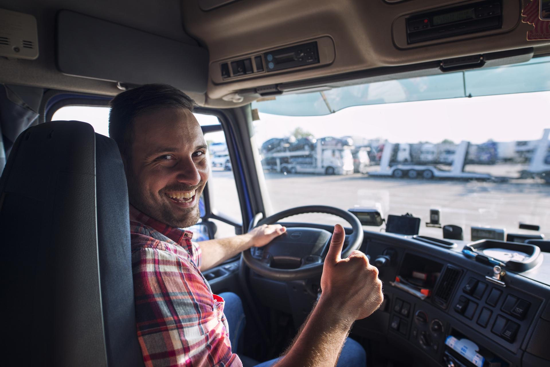 portrait of truck driver sitting in his truck holding thumbs up